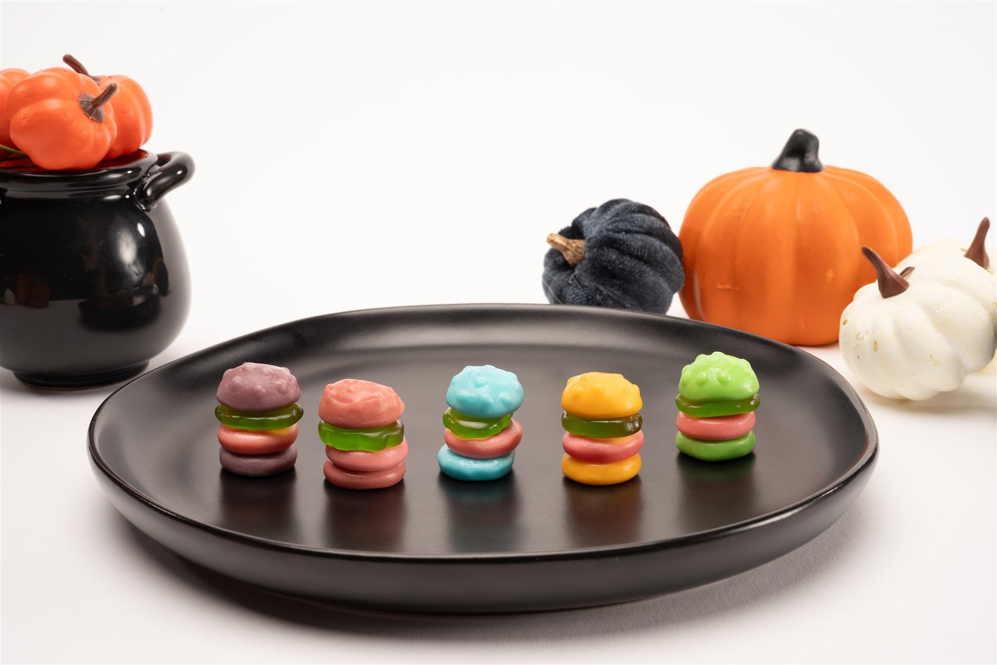 Unwrapped Krabby Patties on a plate in front of pumpkins and a cauldron full of pumpkins.