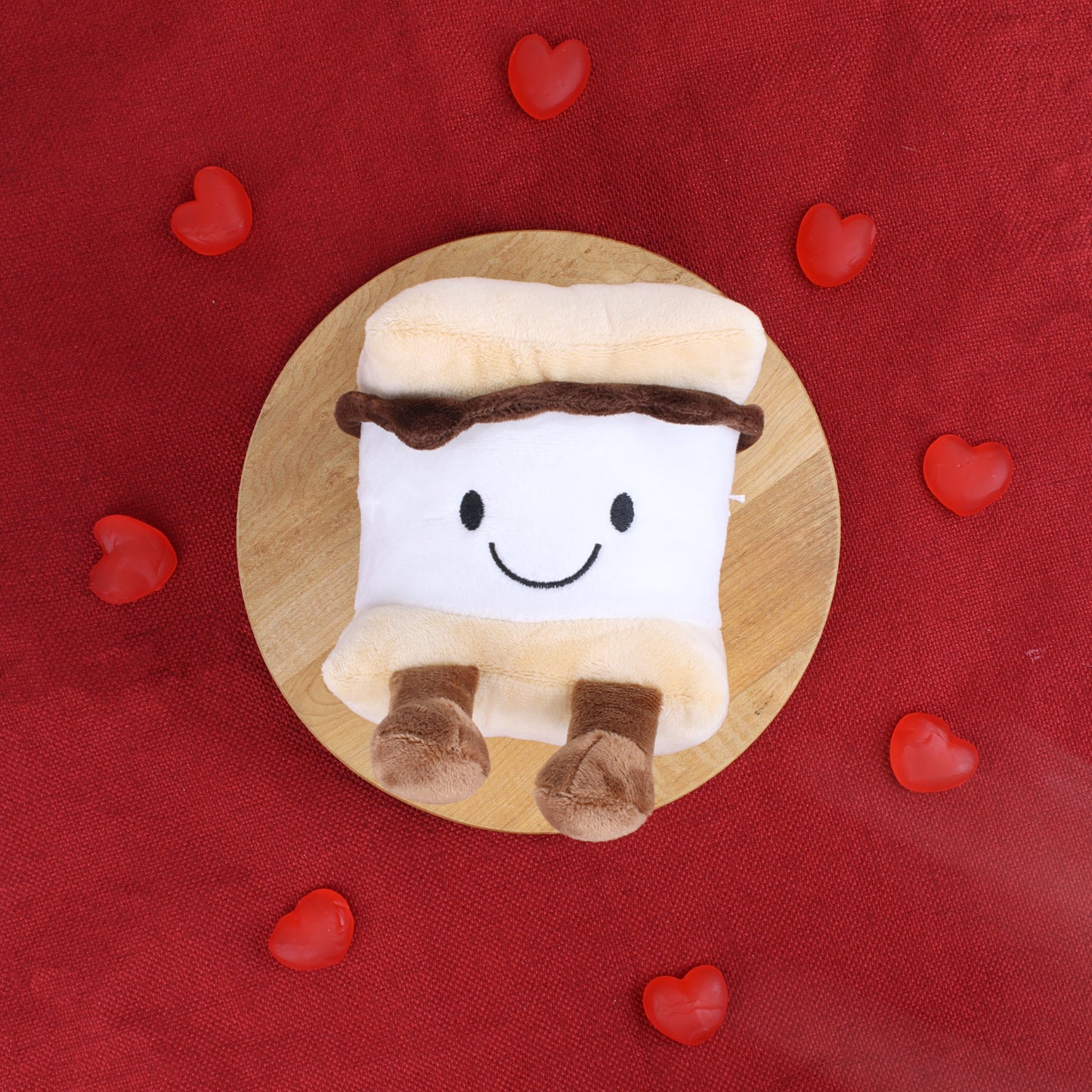 smore plush laid down with gummy hearts in a circle 