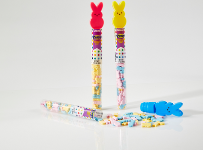 one pink bunny tube topper and one yellow bunny tube toppers standing and filled with colorful hard candies and opened blue bunny tube topper laying down